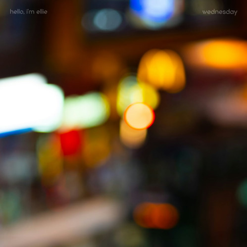 An out-of-focus image of a train at a train station late at night. 'hello, i'm ellie' is at the top left, and 'wednesday' is at the top right.